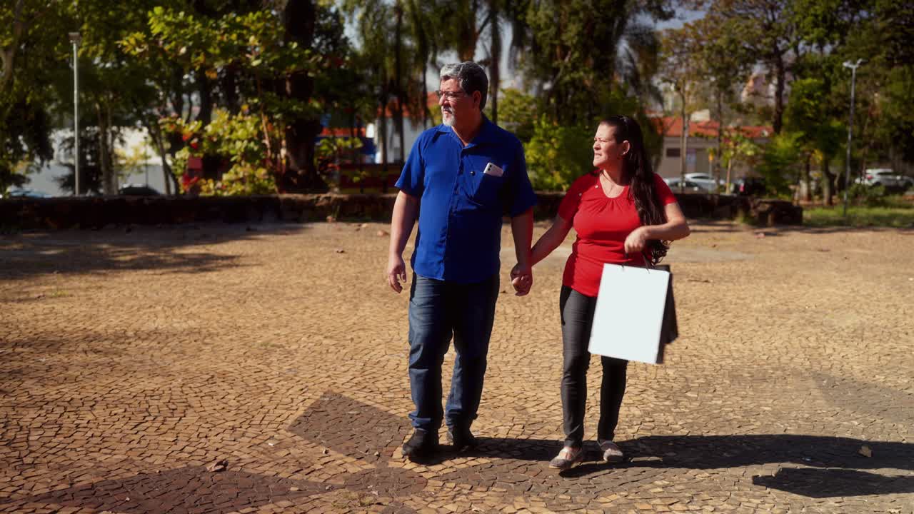 Mature Couple Walking in Park, Holding Hands and Shopping