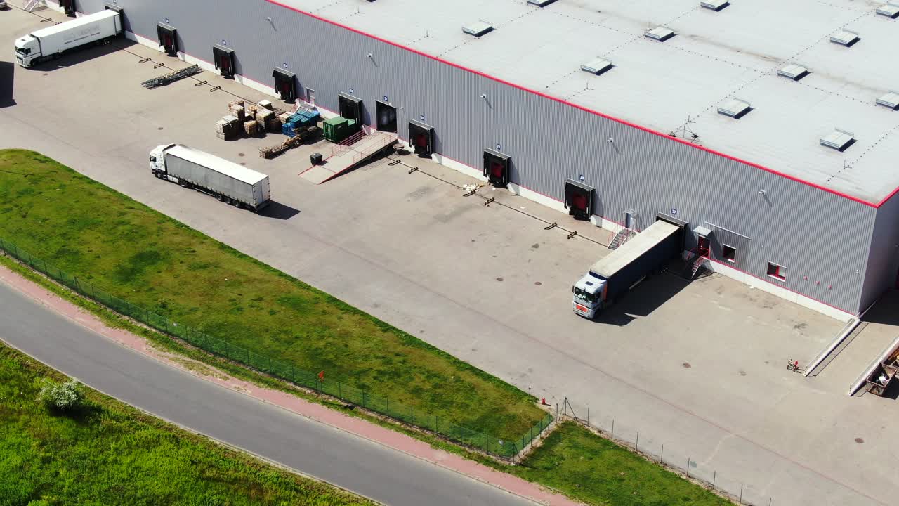 Autoarticolati stazionano sulle rampe del magazzino nel parco logistico con polo di carico e attendono di caricare e scaricare merci al tramonto