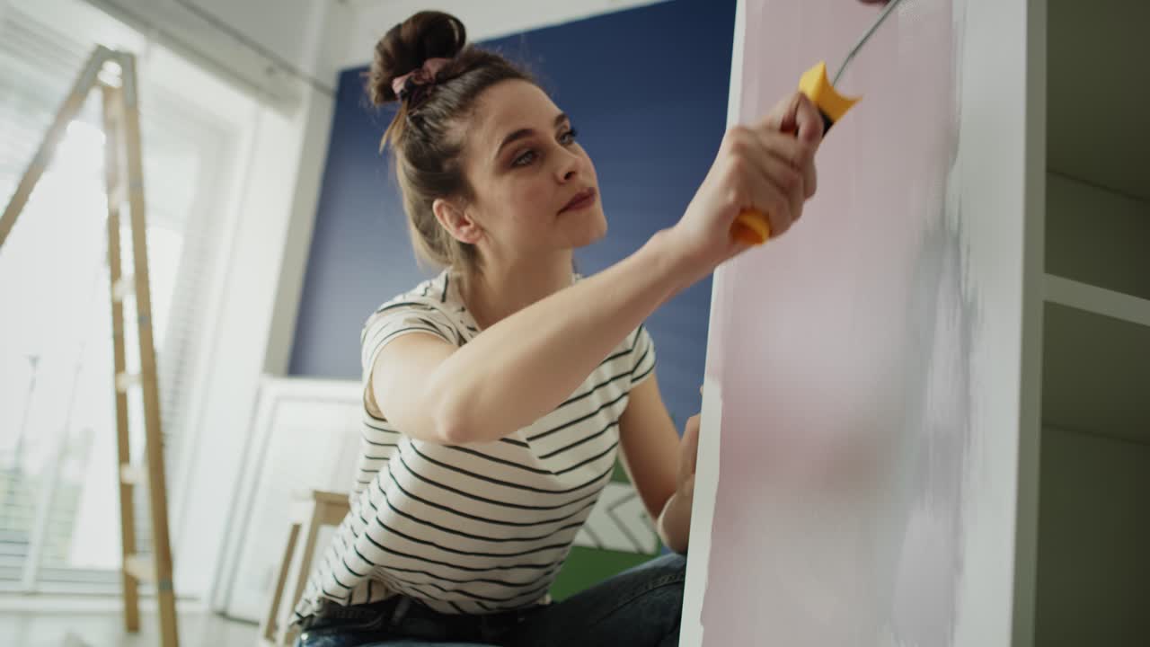 vídeo de seguimiento de una mujer repintando muebles viejos con un rodillo.