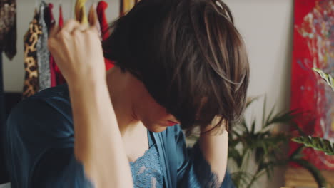 transgender man putting on brunette wig at home