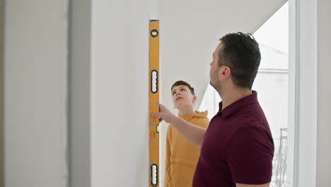 padre e hijo comprobando el nivel de la pared