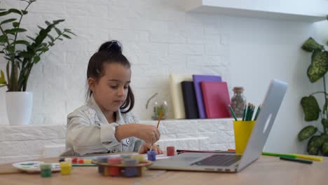 young girl spending a time drawing using online lessons on laptop. distance learning online education