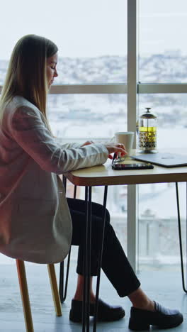 confident happy woman sitting at table and having tea. beautiful woman enjoying lunch break time at work. side view. vertical video