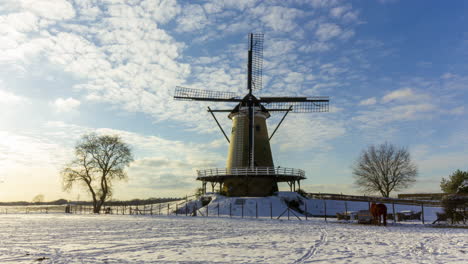 time lapse of clouds passing over traditional windmill in beautiful white winter rural landscape - zoom in