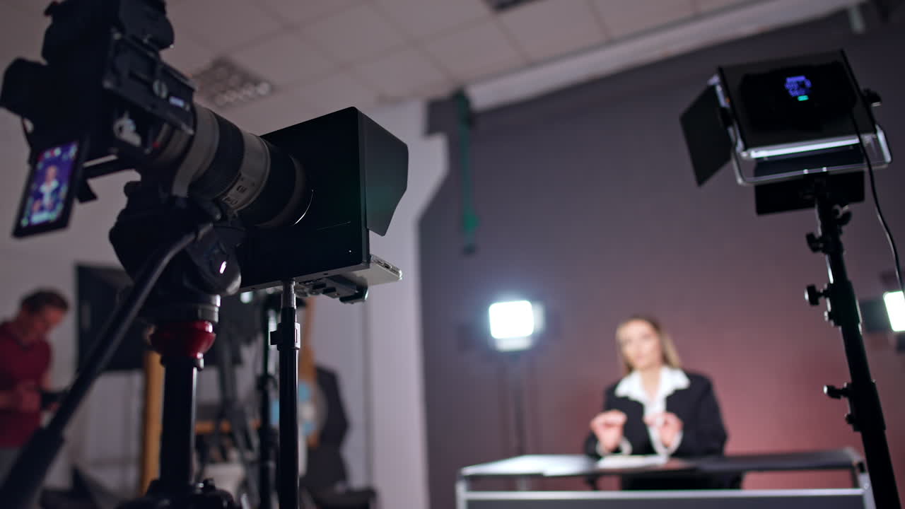 Professional photo equipment in studio. Low angle view. Footage of a woman talking at desk at blurred backdrop.