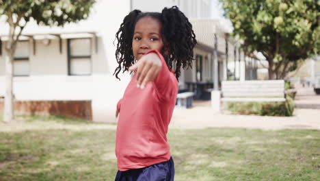 smiling girl pointing outdoors, enjoying playful moment at school playground