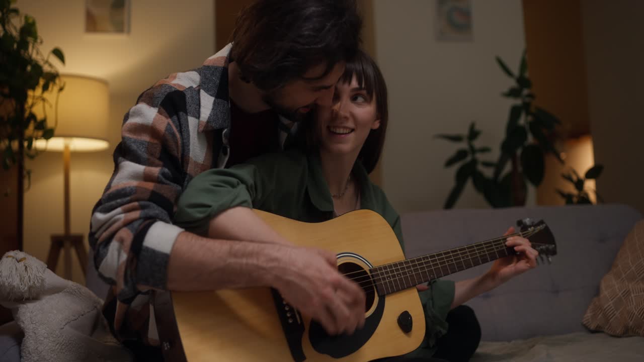 Affectionate couple playing guitar at home