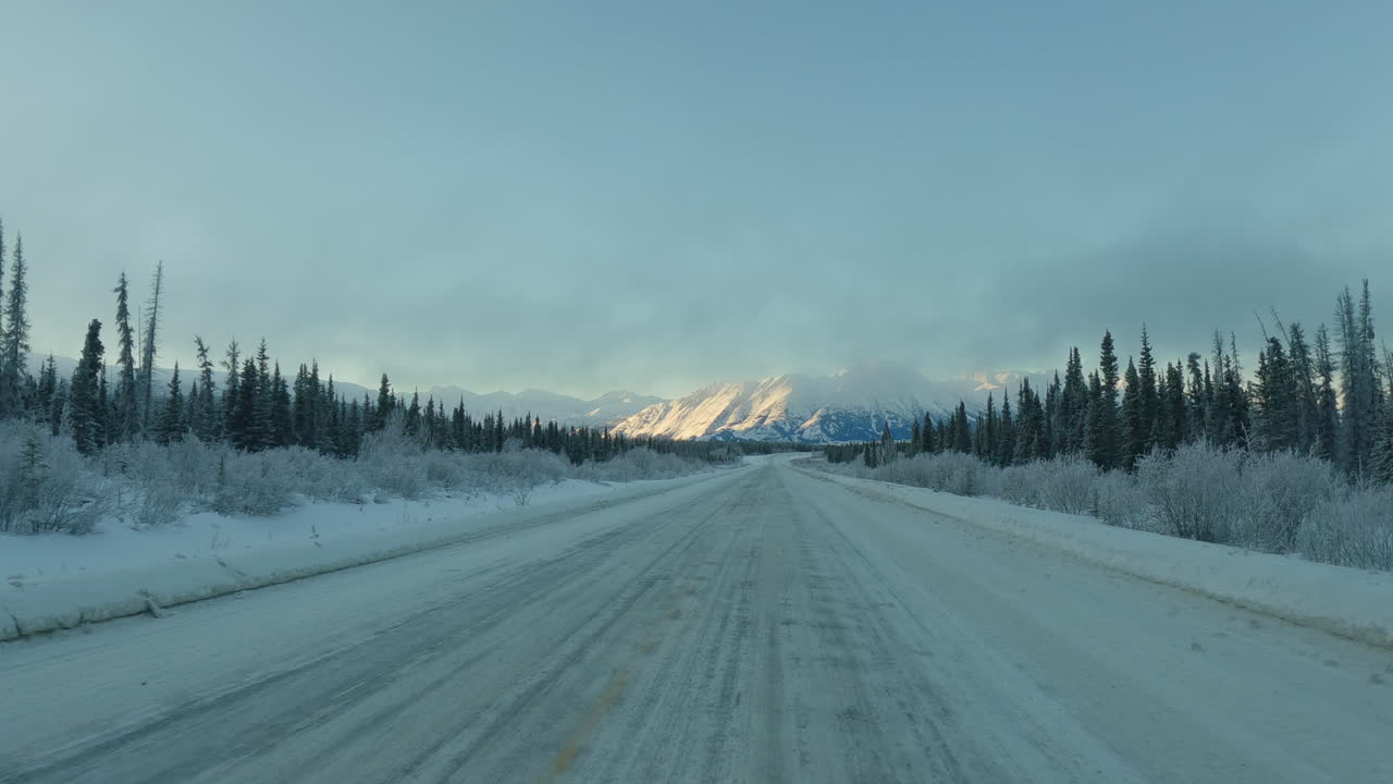 POV From Car Driving Through Snowy Road Along The Pine Tree Forest In Winter In Yukon, Canada.