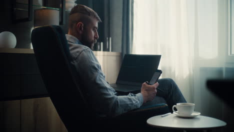 professional financial analyst working on laptop and smartphone in online trading software, analyzing real-time stocks, exchange market charts. successful businessman works in investment bank office.