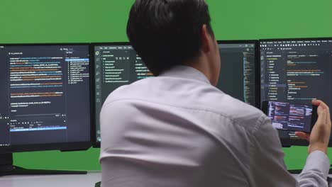 programmer working on multiple monitors and mobile phone