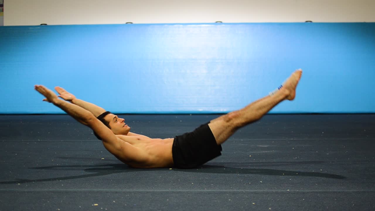 un tipo haciendo un entrenamiento de abdominales en un gimnasio de gimnasia haciendo levantamientos de piernas y manos sin cortos todavía disparados