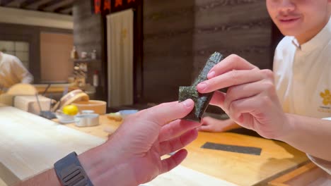 el chef le da sushi al cliente en el mostrador.