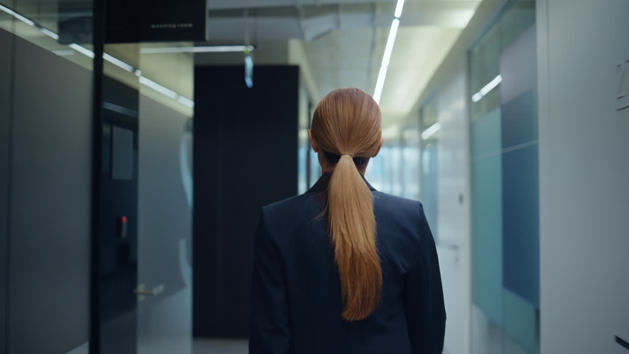Blonde businesswoman strolling hall back view. Smiling lady greeting colleagues
