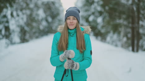 Waist-up-portrait-of-beautiful-young-woman-smiling-happily-looking-at-camera-while-enjoying-skiing-in-snowy-winter-forest,-copy-space