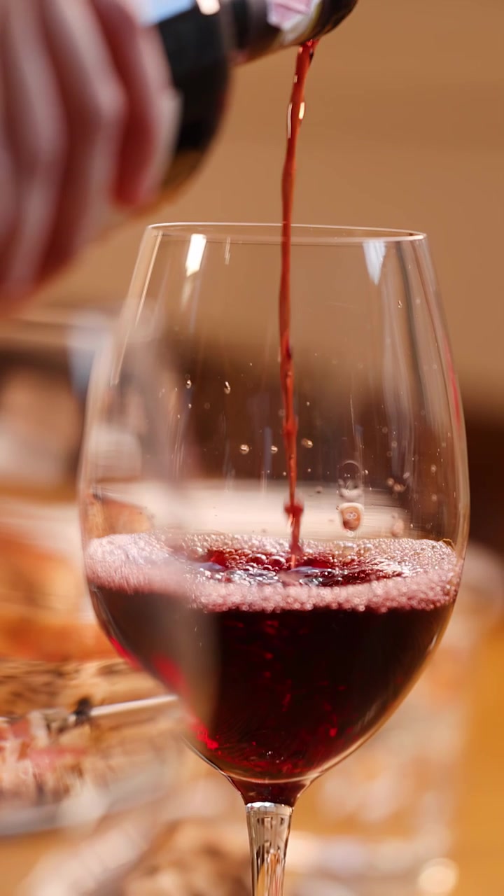 Primo piano di vino rosso versato in un bicchiere durante un elegante pasto al ristorante.