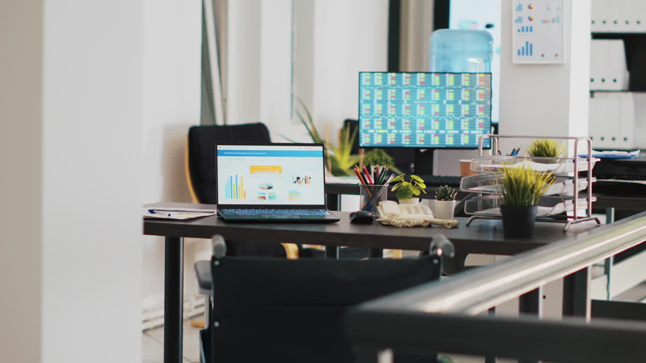 Company workspace with nobody in and business figures on computer monitors
