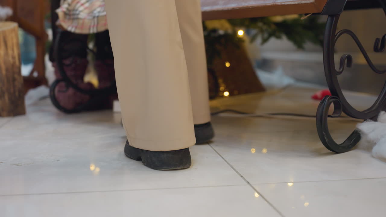 Lower angle view of lady walking towards seat with golden light reflections on polished floor, decorative christmas trees and festive lights adding to holiday atmosphere in shopping mall
