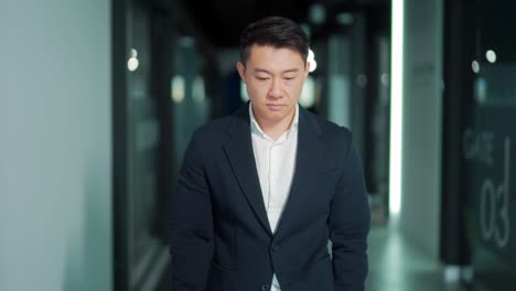 portrait of a successful confident asian male office worker standing and looking at the camera in a formal suit indoors. the face of a business man or entrepreneur employee