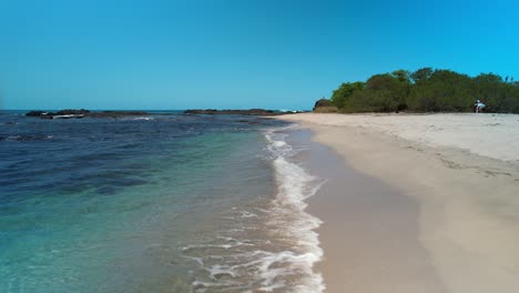 Frau-In-Leuchtend-Rosa-Kleid-Spaziert-Am-Tropischen-Sandstrand-Mit-Türkisfarbenem-Meer-In-Costa-Rica-Entlang,-4k-Luftdrohne