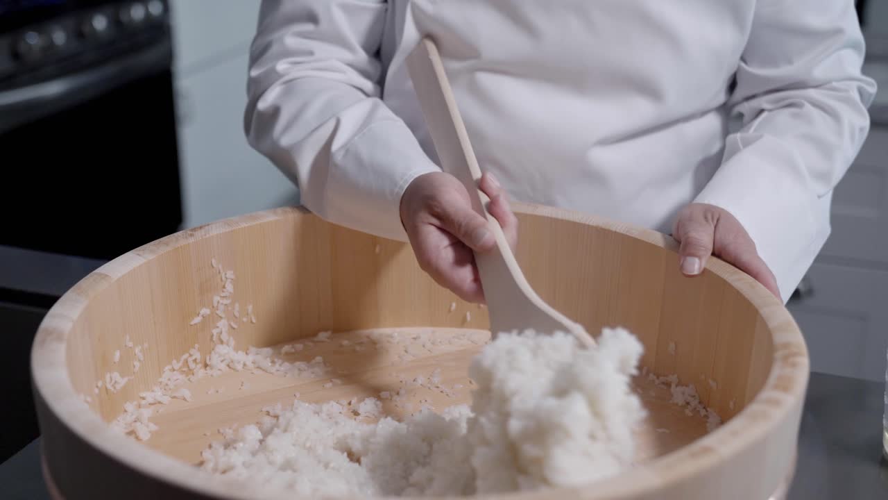 A dynamic shot captures a chef stirring rice and adding oil in preparation for cooking, filmed at 120 fps to highlight the smooth, detailed motion. This footage is ideal for culinary and cooking