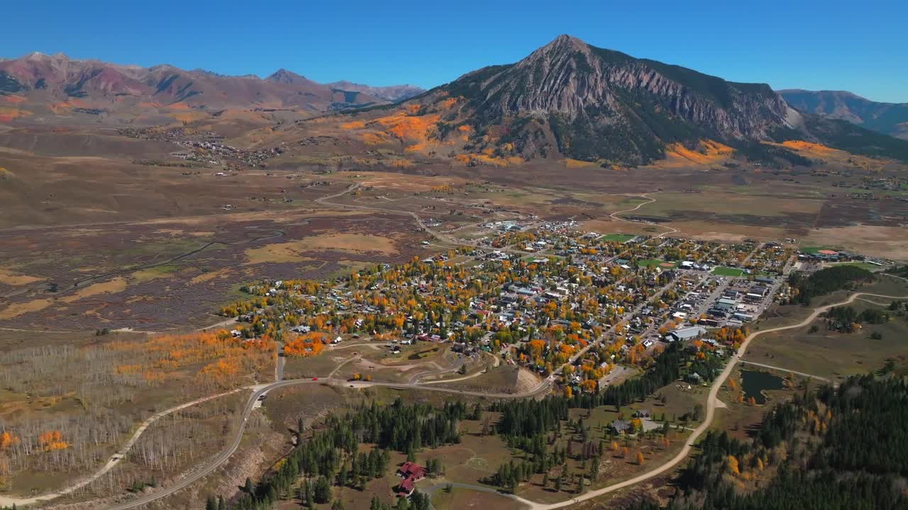 Mount Crested Butte mountain town ski resort Kebler Ohio Pass vibrant Aspen Trees fall autumn auburn peak colors aerial drone Colorado morning Gunnison National forest sunny blue sky forward pan up