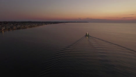 Toma-Aérea-De-Un-Velero-Y-Una-Costa-Lejana-Por-La-Noche