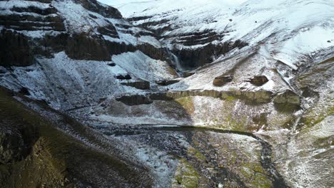 Cascada-En-La-Montaña-Nevada-De-La-Escorrentía-Del-Agua-Del-Glaciar,-Vuelo-Aéreo-De-Drones