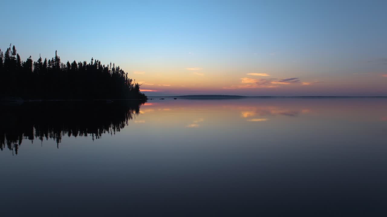 Boat riding on a perfectly calm lake on a late summer evening