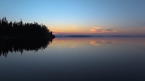 boat riding on a perfectly calm lake on a late summer evening