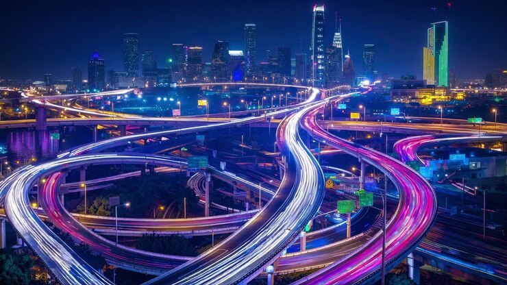 Aerial view of a city at night with vibrant light trails on highways, showcasing dynamic urban life