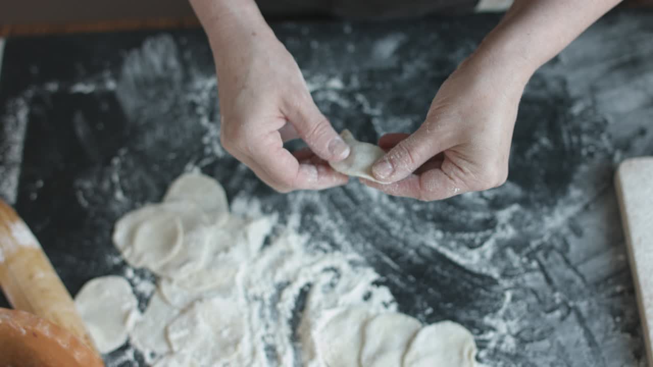 Two hands making meat dumplings.