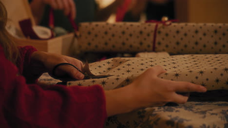 mujer joven cortando papel de regalo en la mesa