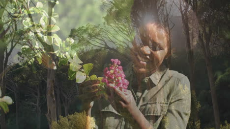 holding pink flowers, woman standing with tree branches visible in background