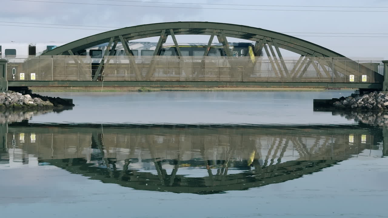 Train Crossing a Green Arch Bridge: Peaceful Reflection in Water