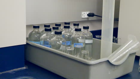 close up on a scientist grabbing a container of distilled water for an experiment in a medical research laboratory