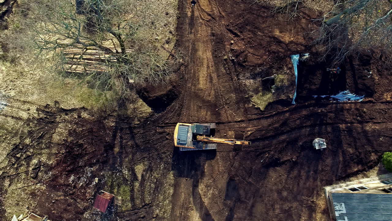 vista de pájaro de drones aéreos de un cargador jcb que prepara el lugar para la futura fundación de la casa para la construcción durante el día
