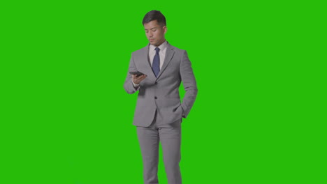 foto de estudio de tres cuartos de longitud de un hombre de negocios con traje que toma una llamada de teléfono móvil contra una pantalla verde 1