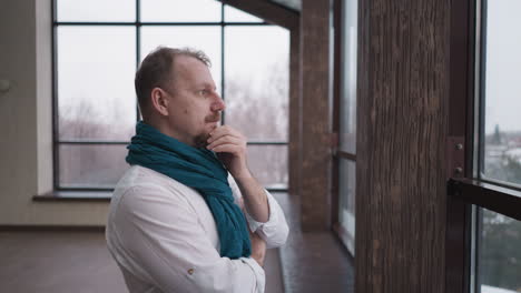 man rubbing beard engages in thoughtful reflection. concentrated man surveys winter panorama beyond window enveloping in tranquil cocoon of contemplation