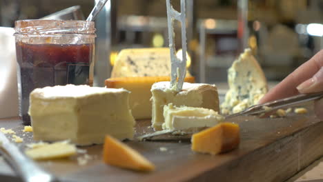 hands cutting soft cheese with knife