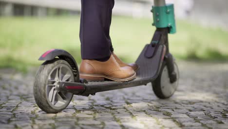 sección baja de hombre de negocios montando scooter al aire libre