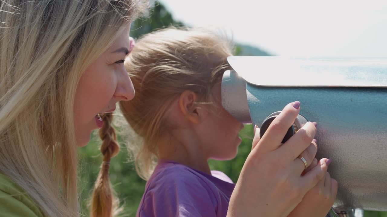 타워 뷰어를 통해 보는 아이를 가진 행복한 금발 여성