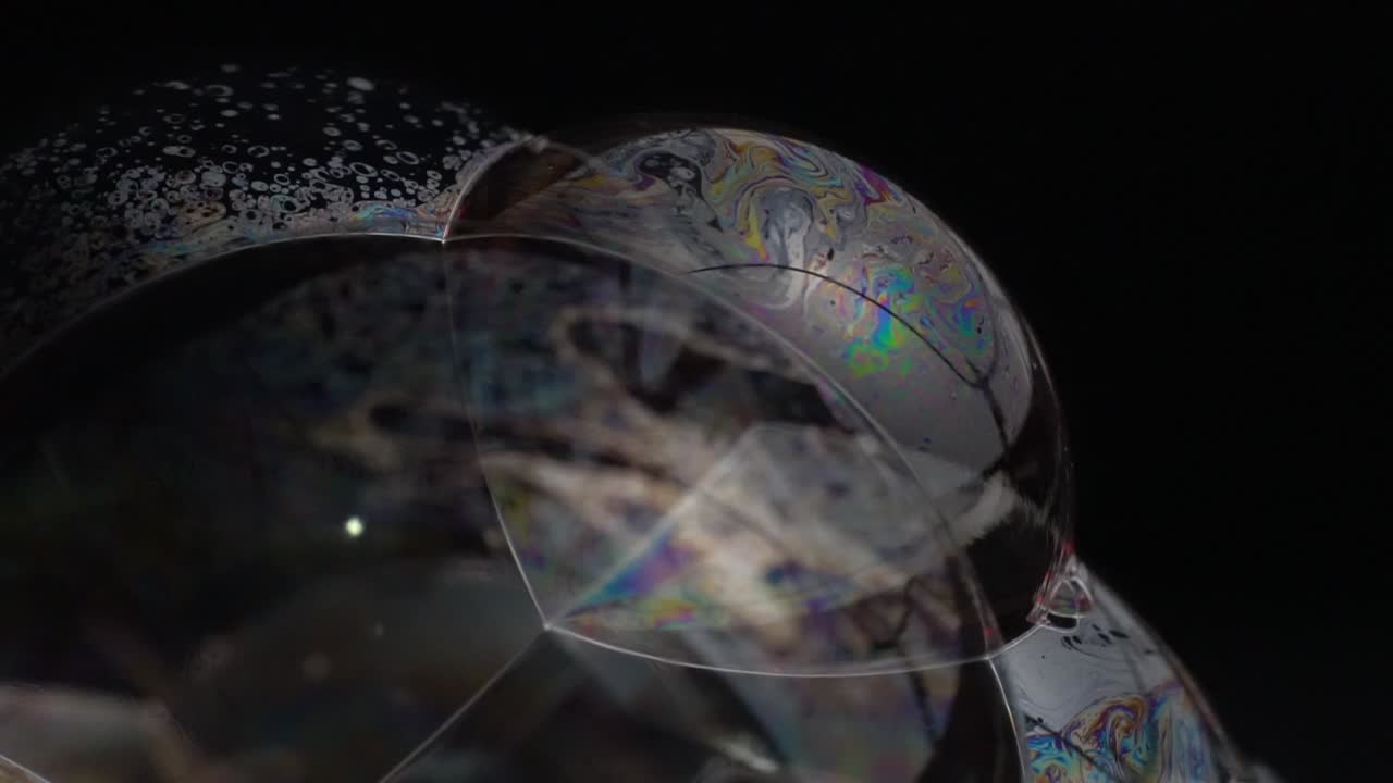 primer plano de burbujas de jabón sobre un fondo oscuro, destacando sus superficies translúcidas con colores sutiles y patrones intrincados