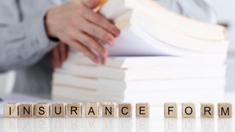 woman sorting documents on background of wooden cubes with word insurance forms 4k movie slow motion