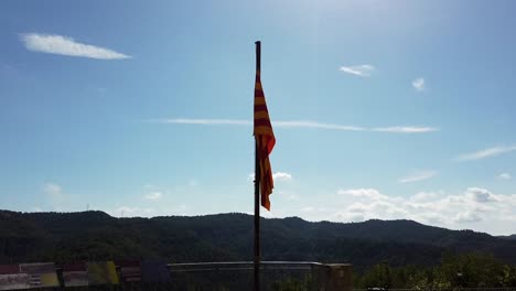 zoom in on catalan flag barely moving on top of a hill, overlooking hills with a cloudy sky