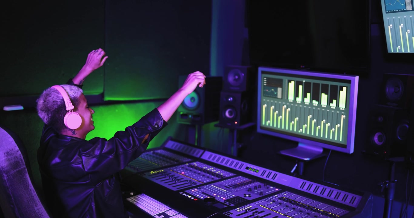 Excited Music Producer Celebrating Success in a Neon Lit Recording Studio
