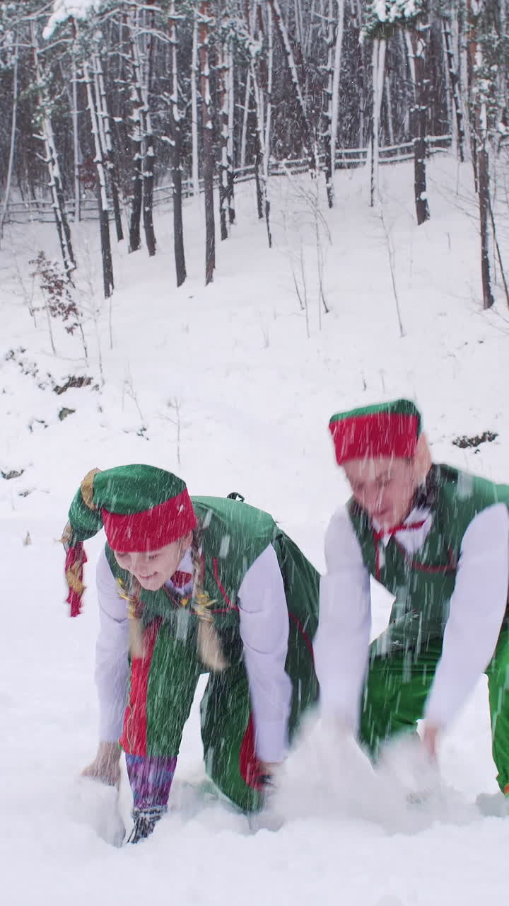 Funny elves are happy with fresh snow tossing it up. Santa claus residence before christmas. Vertical video