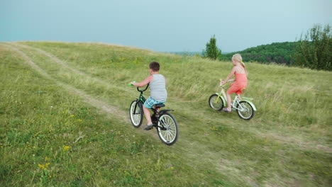 the girl and the boy are having fun riding up the hill on bicycles