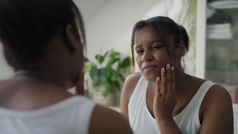 african-american woman  in the bathroom having a strong toothache or bruxism.