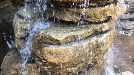 slow motion footage of water droplets, running water, trickles, splashes, drops, and waterfalls surrounded by rock and other hard earthen material
