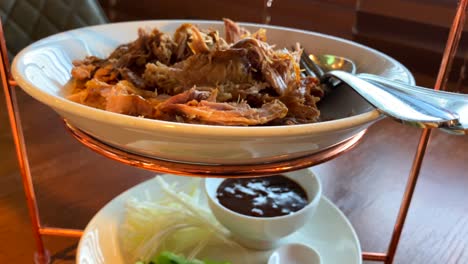 pato de pekín crujiente tradicional con panqueques al vapor, cebolla, pepino y salsa hoisin, delicioso plato asiático servido en una torre de bandejas de tres pisos, tiro de 4k